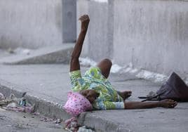 Una mujer pide ayuda tras resultar herida en una pierna a causa de un tiroteo en Puerto Príncipe.