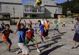 Un grupo de chicos juega con un balón en una plaza.