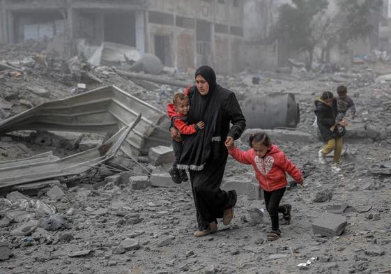 Una madre abandona con sus hijos un barrio de Gaza bombardeado por Israel.