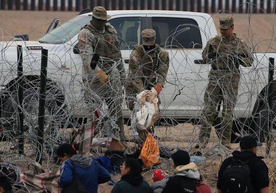 Guardias fronterizos esperan tras una alambrada de navajas y púas mientras migrantes intentan pasar a Texas.