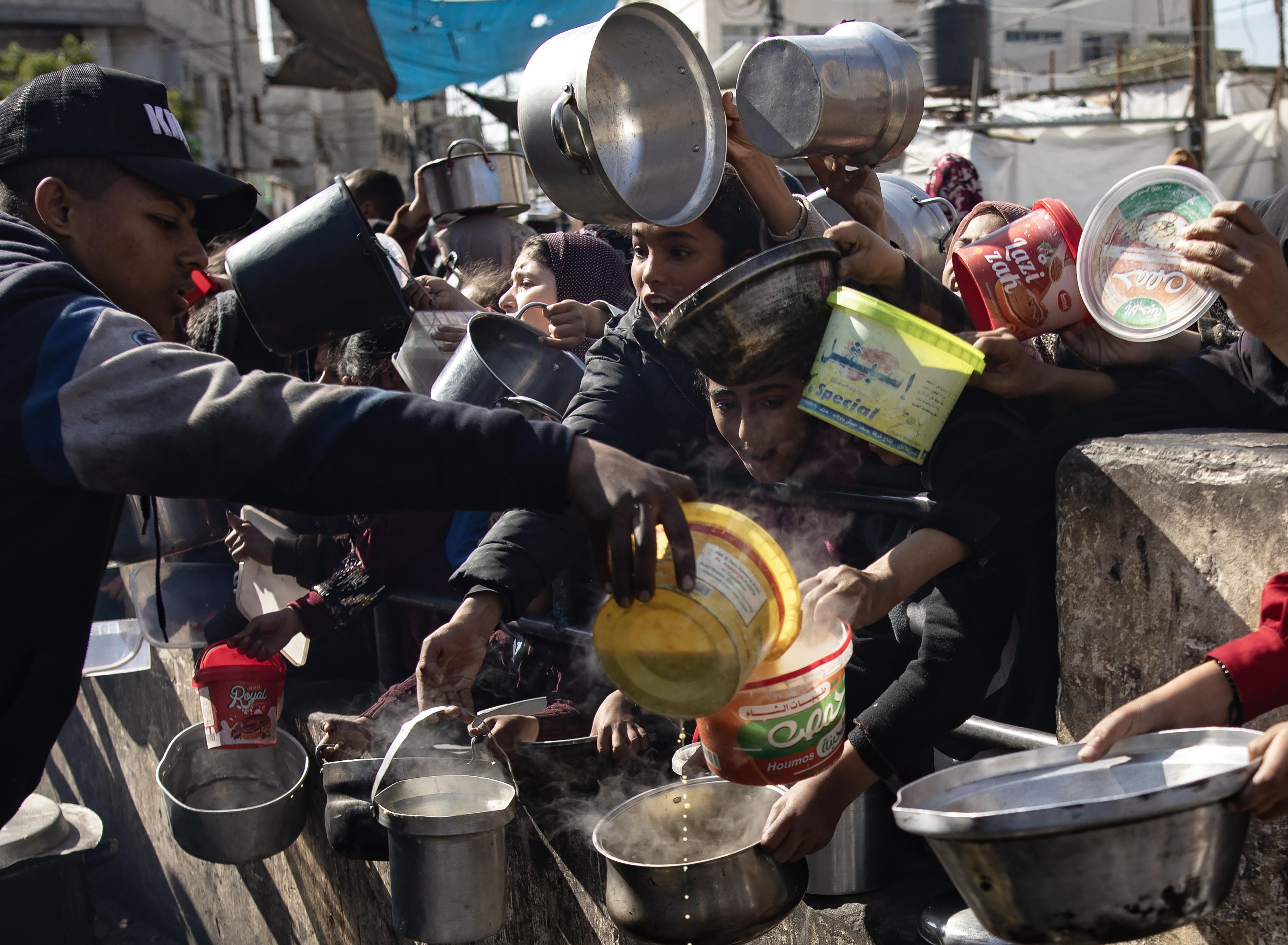 Palestinos con cazuelas para recibir alimentos en el campo de refugiados de Rafah