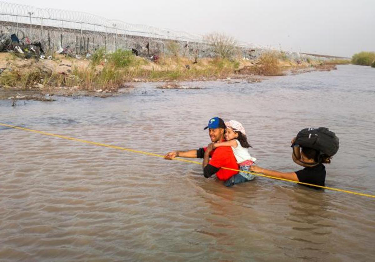 Una familia de migrantes cruza el río Grande desde México a Texas.