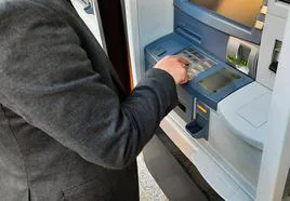 Un hombre saca dinero en efectivo de un cajero automático.