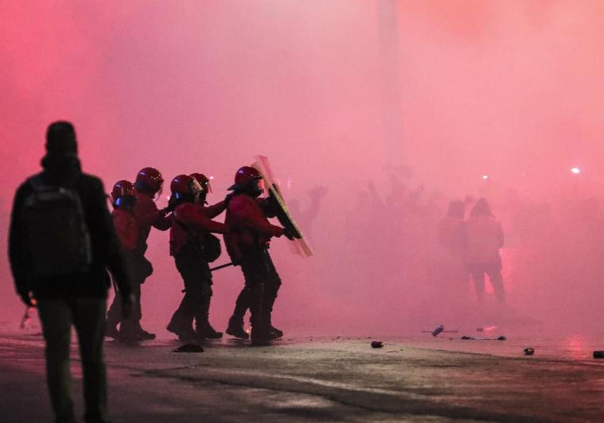 Agentes de la Ertzaintza se protegen ante el lanzamiento de objetos por parte de los ultras del Athletic en los aledaños de San Mamés.