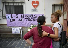 Unas vecinas colocan flores para recordar a una de las menores asesinadas por su padre en Almería.