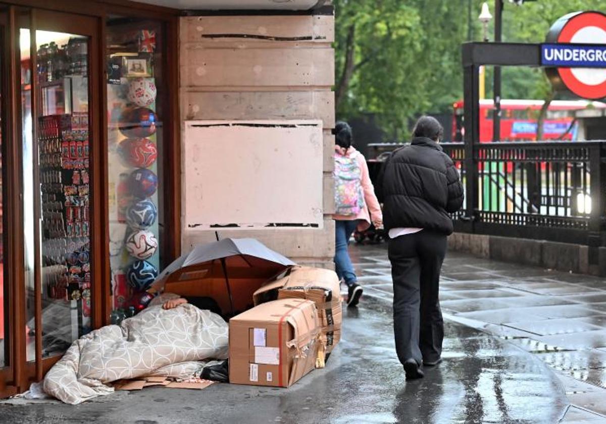 Un 'sintecho' duerme a la entrada de un comercio, en los aledaños de una entrada del metro de Londres.