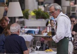 Un camarero sirve a una pareja de turistas en Madrid.