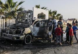 Varios hombres y niños palestinos observan los restos de uno de los vehículos atacados por el ejército israelí.