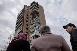 Vecinos de Járkov observan el edificio residencial dañado por los bombardeos rusos.