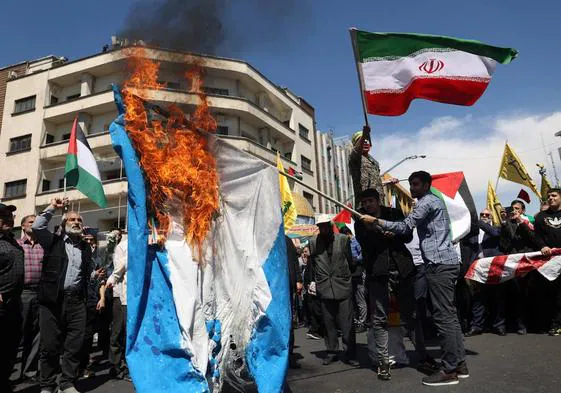 Iraníes queman una bandera israelí durante una manifestación tras el ataque contra su embajada en Damasco.