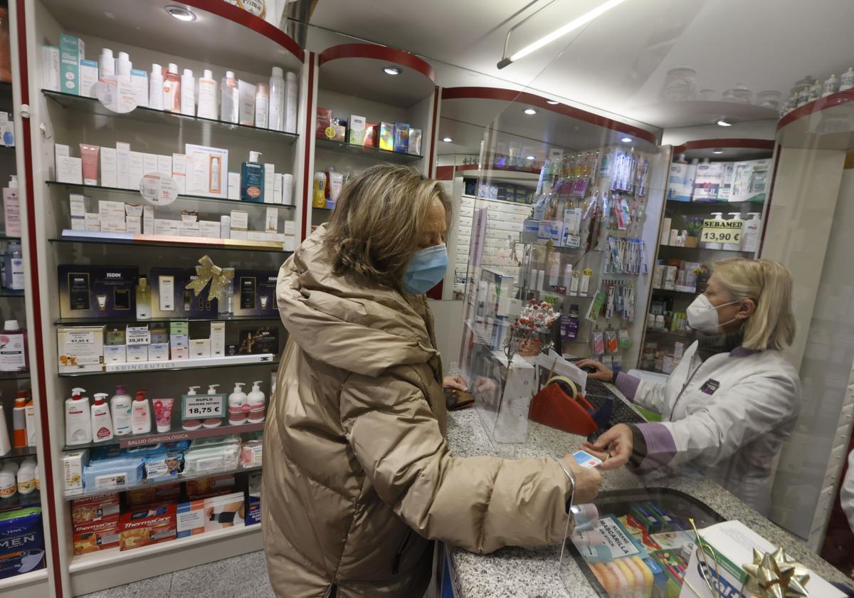 Una clienta compra un medicamento en una farmacia.