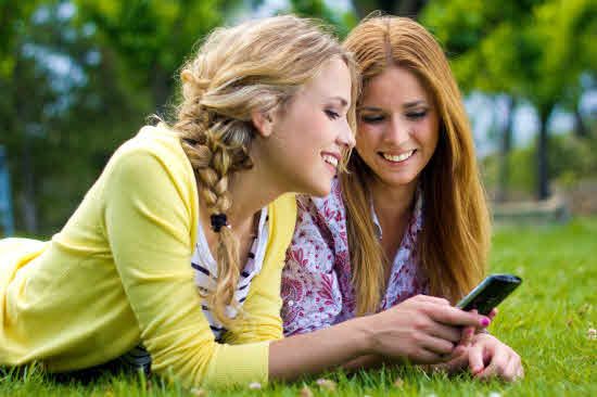 Dos adolescentes mirando un móvil.