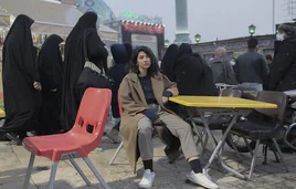 Una joven, con gesto triste, rodeada de mujeres con la cabeza cubierta en Teherán.