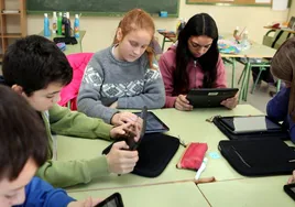 Un grupo de alumnos maneja sus tabletas en clase.