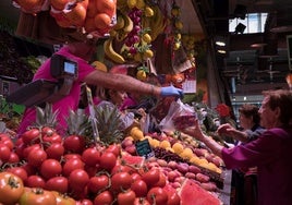 Varios ciudadanos compran en una frutería.