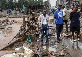 Varias personas observan el cadáver de un hombre descubierto cuando el río Gitathuru retrocedió tres días después de que las fuertes lluvias lo desbordaran dañando los barrios circundantes, en Mathare, Nairobi.