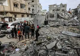 Varios niños y jóvenes gazatíes, junto a las ruinas de un edificio en Rafah.
