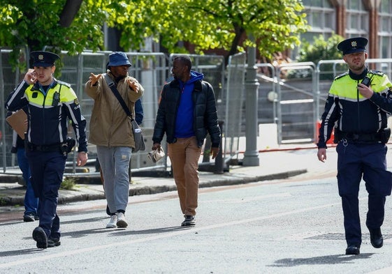 La Policía irlandesa acompaña a dos solicitantes de asilo por las calles de Dublín.