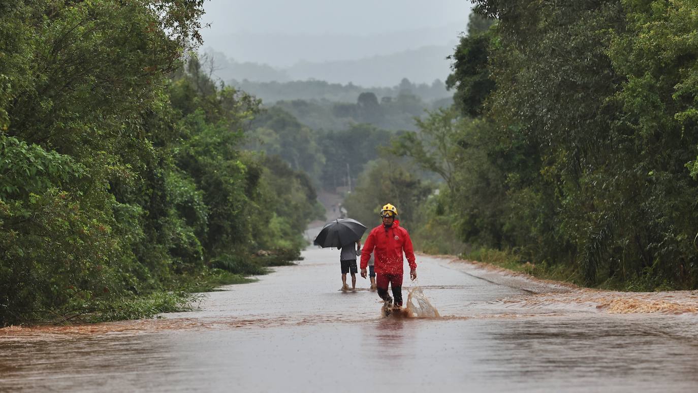 Dos personas caminan sobre una carretera inundada.