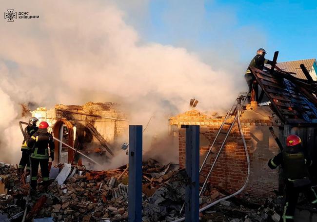 Bomberos extinguen un incendio en una vivienda bombardeada en la región de Kiev.