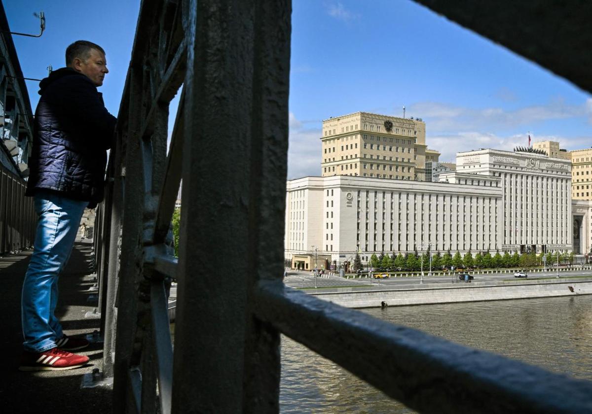 Un hombre mira desde un puente que cruza el río Moskva frente a la sede del Ministerio de Defensa ruso.