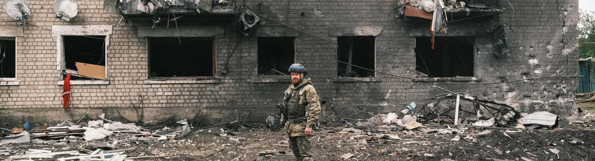 A soldier poses in front of the charred remains of a building on the outskirts of Kharkiv.