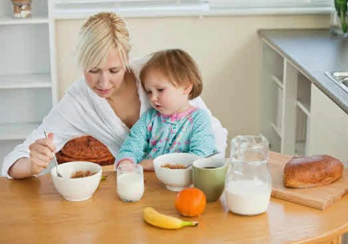 Madre dando el desayuno a su hija.