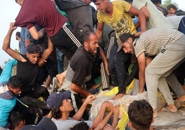 Un grupo de hombres tratan de hacerse con algo de la ayuda llegada al muelle construido por EE UU.