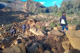 Vecinos y rescatistas sobre la masa de roca y tierra que cubre la aldea.