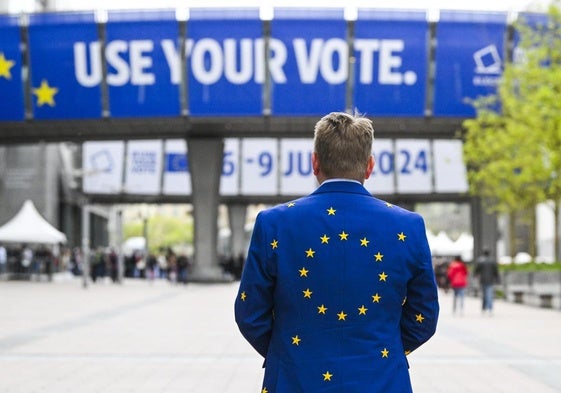 Un hombre vistiendo una chaqueta europea frente a la sede del Parlamento Europeo.