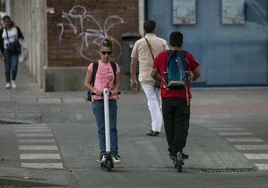 Personas circulando con un patinete eléctrico.