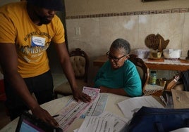 Un funcionario de la Comisión Electoral Independiente muestras las papeletas a una mujer en Johannesburgo.