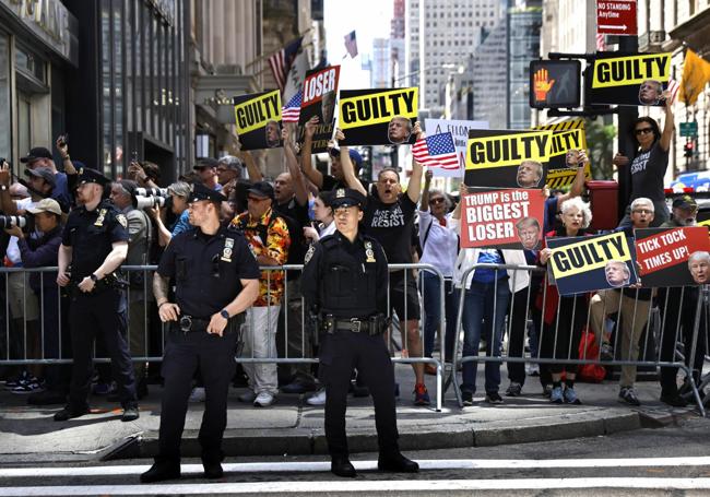 Manifestantes anti Trump exhiben pancartas tras la rueda de prensa ofrecida por el magnate.