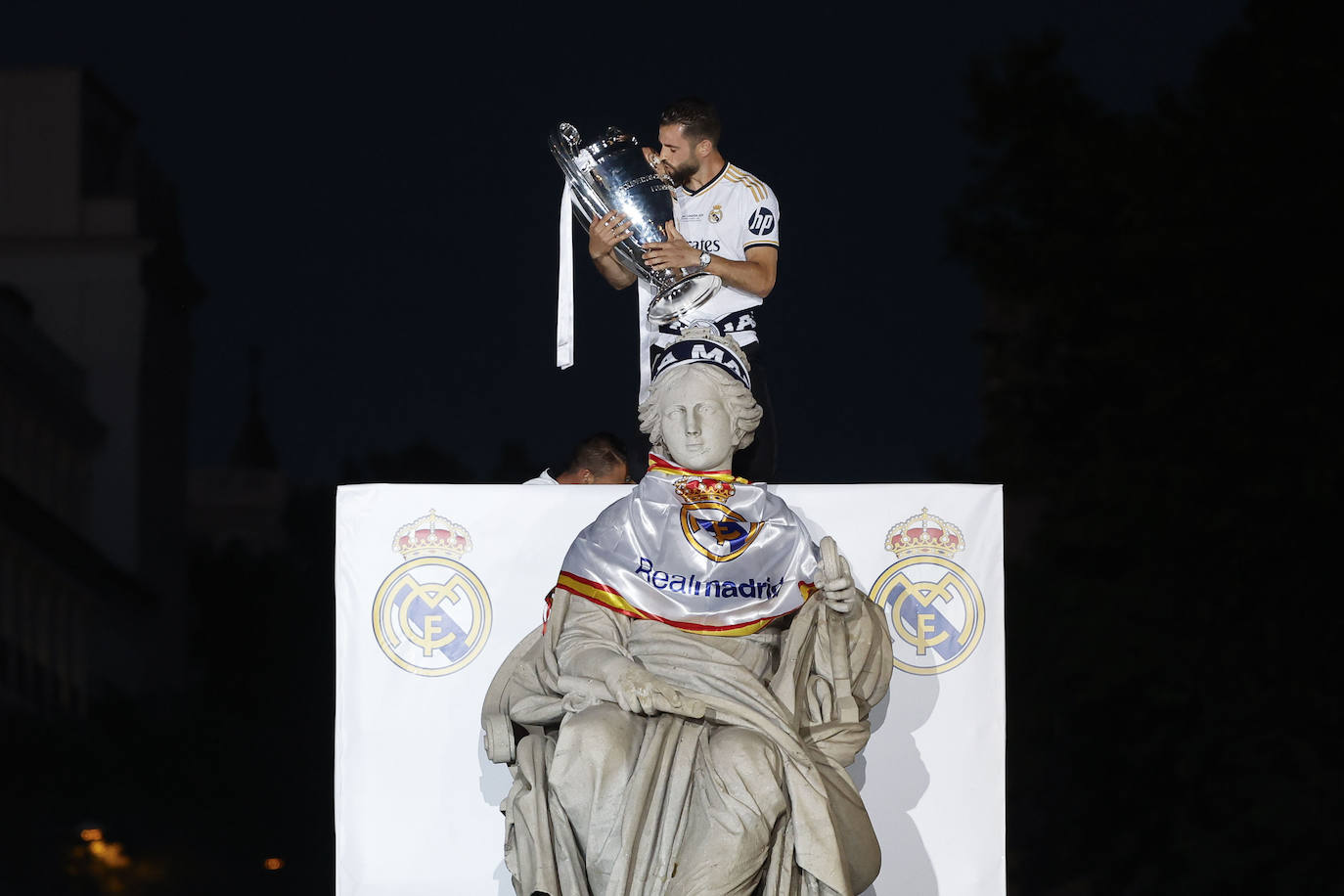 Nacho, capitán del Real Madrid, besa el trofeo de la Liga de Campeones después de colocarle una bufanda y una bandera a la diosa Cibeles.