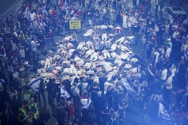 Un grupo de manifestantes simula la muerte de los rehenes israelíes durante la gran marcha de Tel Aviv que reclama su liberación.