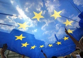 Varias personas sujetan una bandera de la Unión Europea.