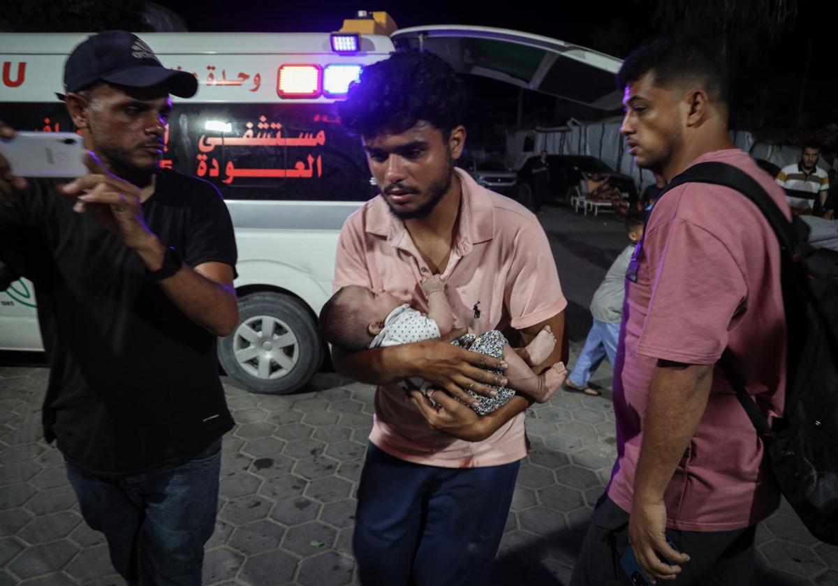 Un padre traslada a un hospital a su bebé herido en un bombardeo.