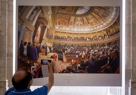 Un visitante fotografía la imagen de la ceremonia de coronación de Felipe VI en el Congreso.