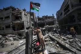 Dos jóvenes levantan una bandera palestina junto a su casa destruida tras un bombardeo israelí en el sur de Gaza.