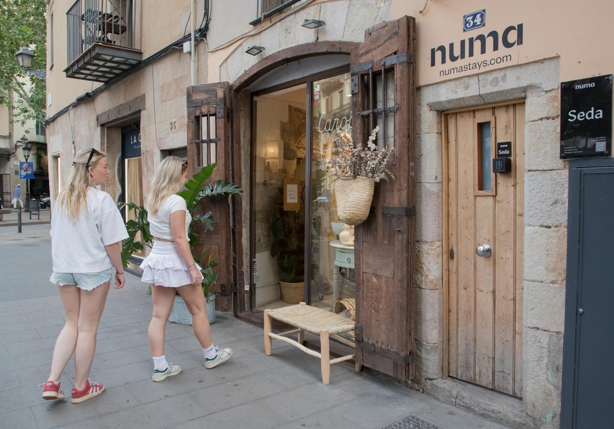 Dos turistas, junto a la entrada de un piso turístico en el centro de Barcelona.