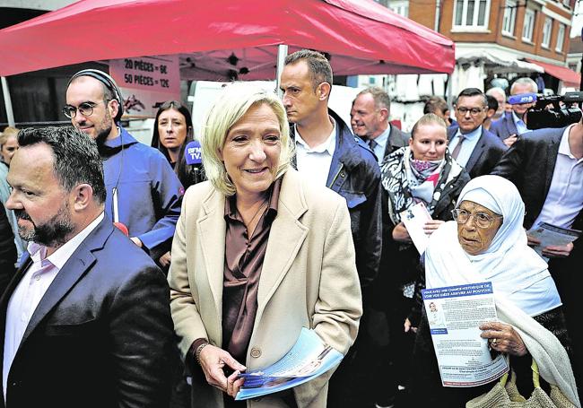 Marine Le Pen reparte propaganda electoral en un mercado.