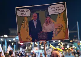 Una manifestante israelí sostiene una pancarta que representa a Netanyahu y su esposa.