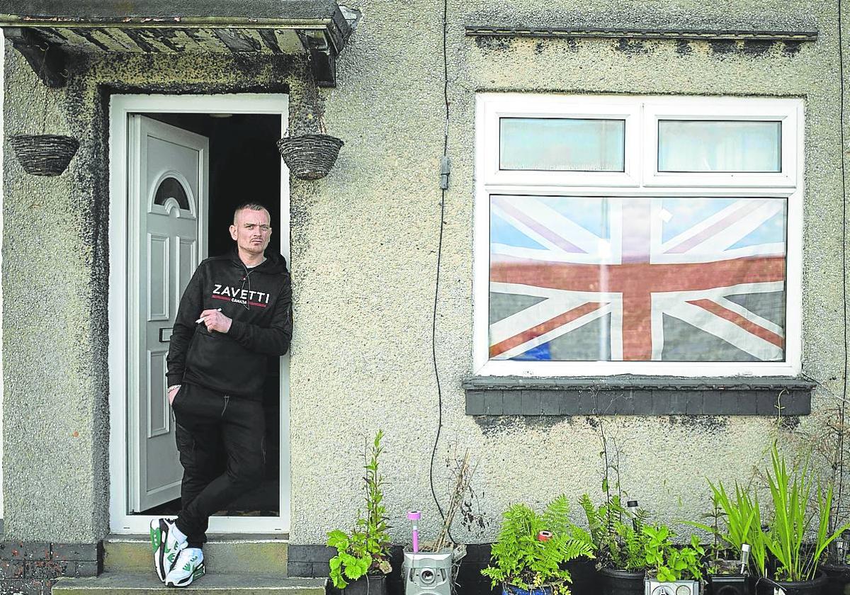 Un vecino de Keighley, en el noroeste de Inglaterra, fuma en la puerta de su hogar.