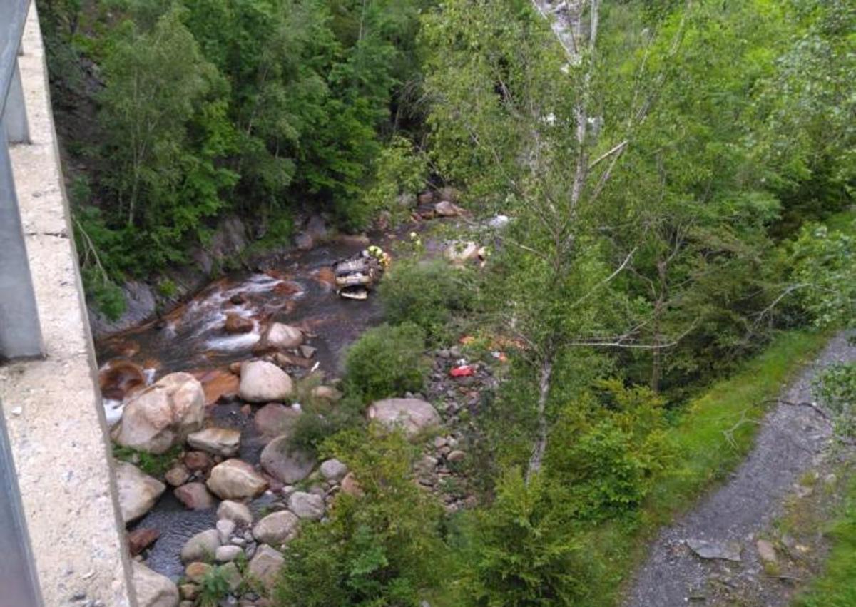 Imagen secundaria 1 - Vista de la zona del accidente desde el río Ésera y trabajos de los bomberos para tratar de rescatar del coche siniestrado los cuerpos de las tres víctimas mortales.