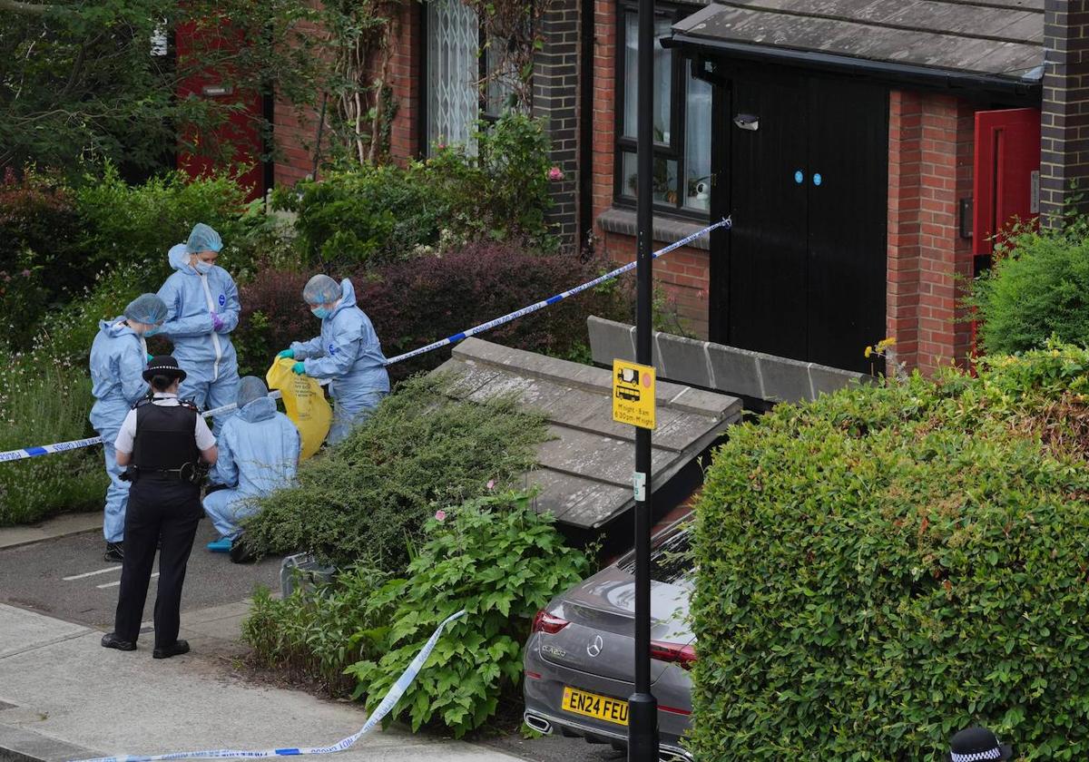 Agentes forenses trabajan en la entrada de la vivienda de Londres donde apareció una de las maletas.