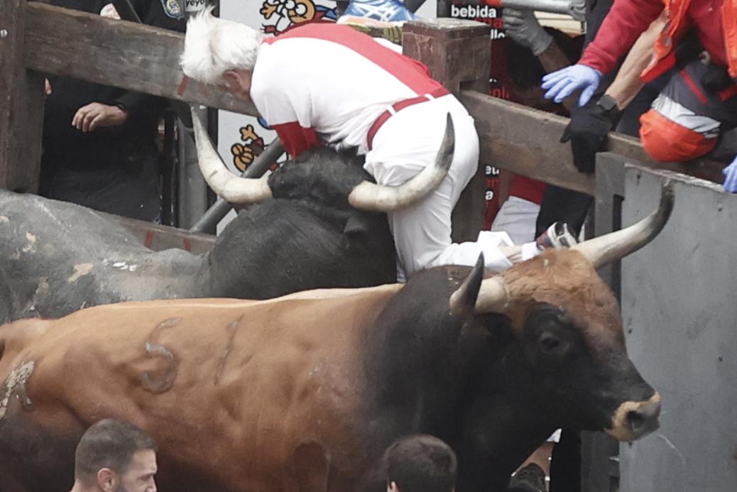 Un mozo es embestido por uno de los toros de la ganadería sevillana de Miura durante el último encierro de los Sanfermines 2024.