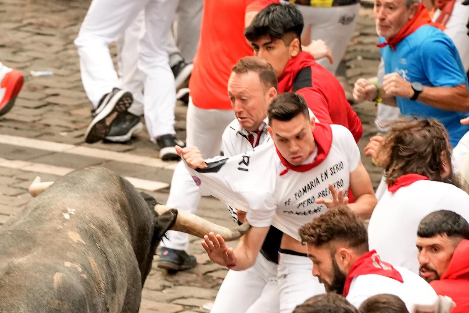 Un Miura alcanza por la manga de la camiseta a uno de los mozos, sin llegar a ser corneado.