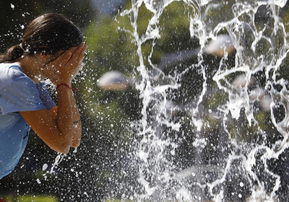 Una mujer se refesca en una de las fuentes de Córdoba.