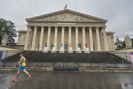 Un corredor pasa frente al edificio de la Asamblea Nacional francesa, en París.