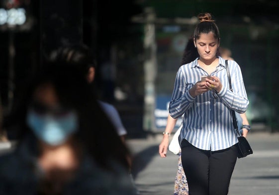 Una joven camina con su móvil.